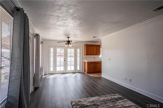 unfurnished living room featuring baseboards, visible vents, dark wood-style floors, a textured ceiling, and french doors