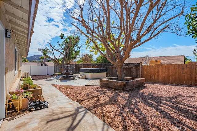 view of yard featuring a hot tub, a fenced backyard, and a patio