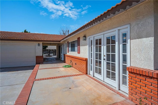 view of patio / terrace with french doors, driveway, and an attached garage