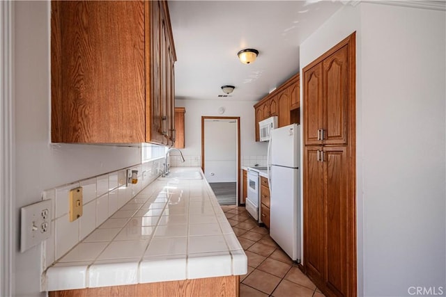 kitchen featuring tile countertops, white appliances, a sink, brown cabinets, and tasteful backsplash