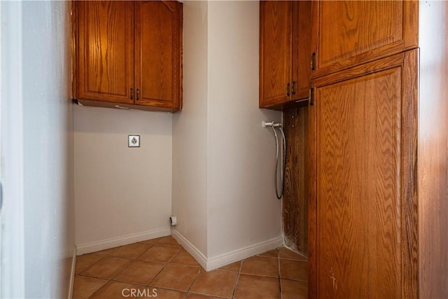 laundry room with cabinet space, hookup for an electric dryer, baseboards, and light tile patterned floors