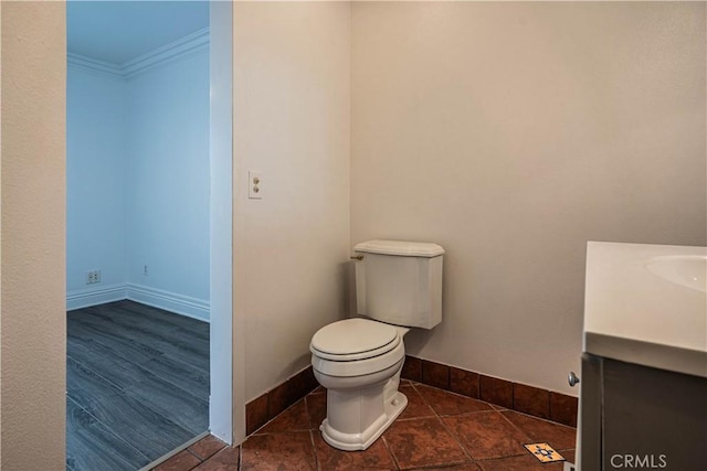 bathroom with baseboards, crown molding, vanity, and toilet