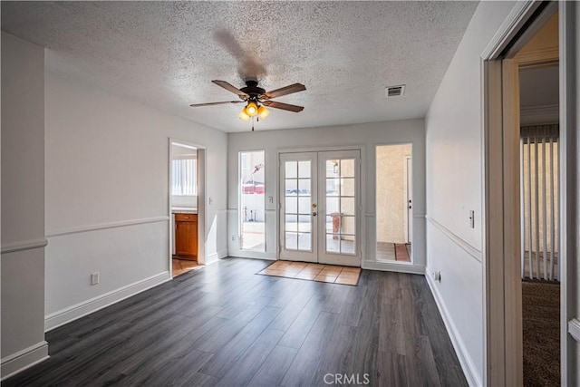 spare room featuring visible vents, dark wood finished floors, ceiling fan, a textured ceiling, and french doors