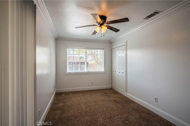 carpeted empty room featuring a ceiling fan, baseboards, visible vents, and crown molding