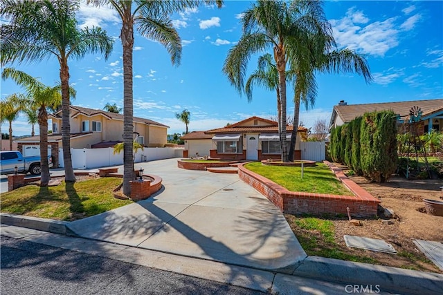 view of front facade with fence, concrete driveway, and a front yard