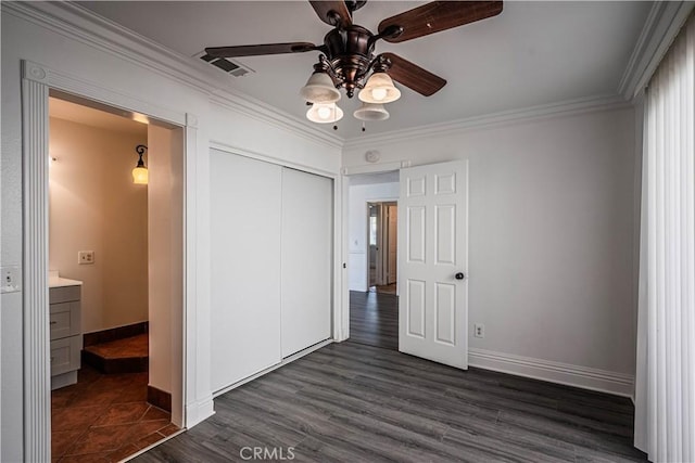 unfurnished bedroom with visible vents, baseboards, a closet, dark wood finished floors, and crown molding