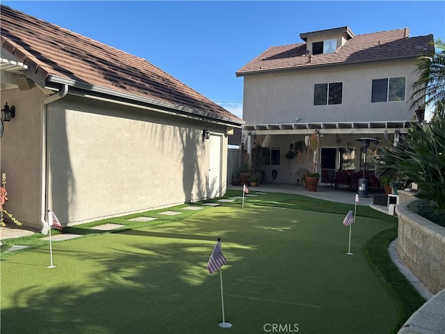 rear view of house with stucco siding, a tiled roof, and a patio