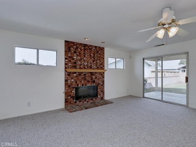 unfurnished living room featuring carpet, ceiling fan, a fireplace, and visible vents