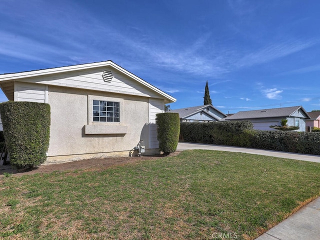 view of side of home featuring a lawn and stucco siding