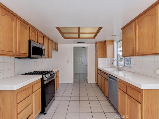 kitchen with visible vents, tile counters, appliances with stainless steel finishes, and a sink