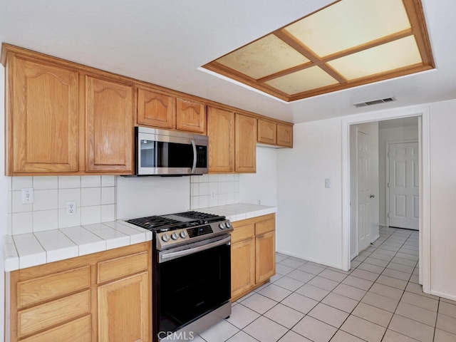 kitchen with light tile patterned floors, tasteful backsplash, visible vents, tile countertops, and stainless steel appliances