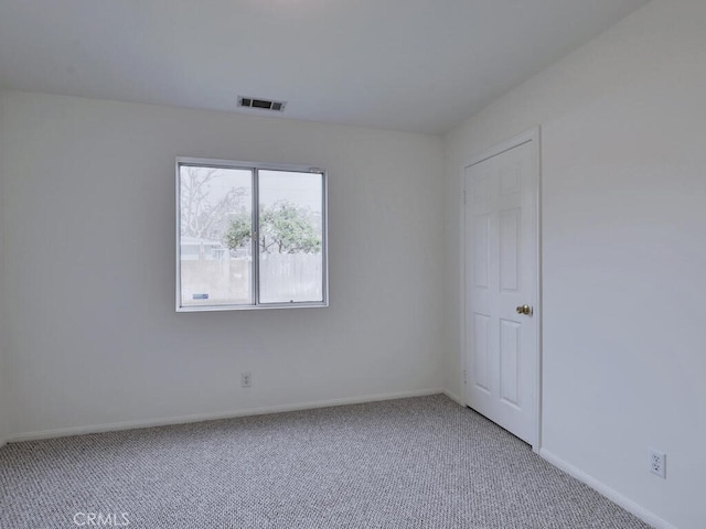 spare room featuring baseboards, visible vents, and light colored carpet