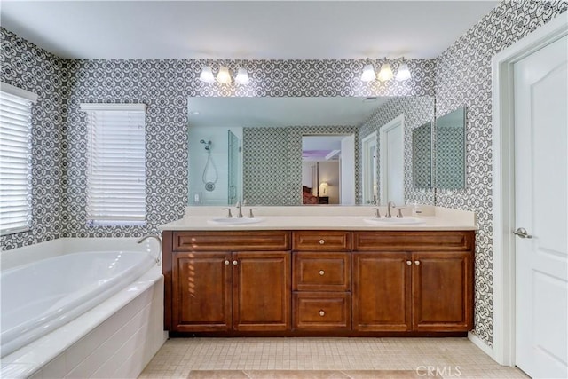 bathroom with double vanity, a garden tub, a shower stall, and a sink