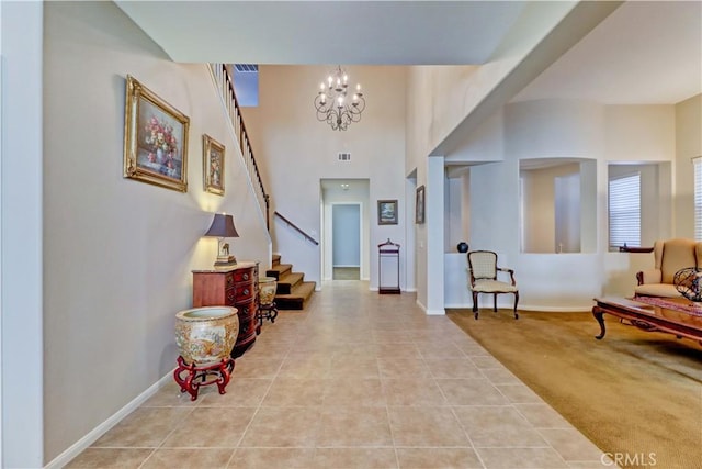 foyer entrance featuring baseboards, stairway, tile patterned floors, carpet, and a notable chandelier