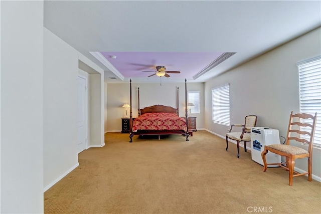 bedroom featuring a raised ceiling, light colored carpet, a ceiling fan, ornamental molding, and baseboards