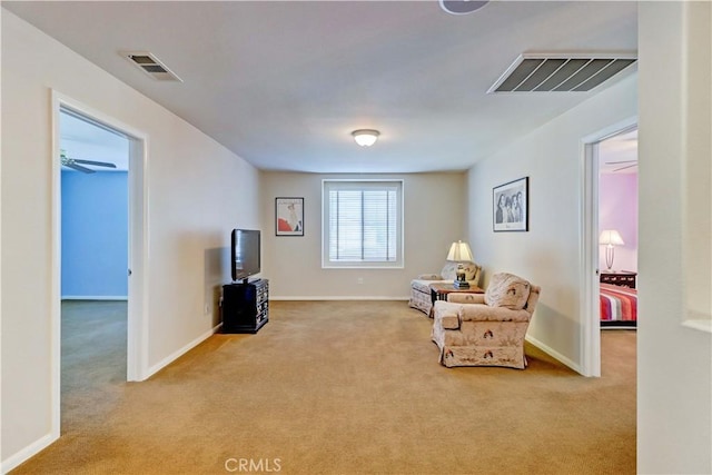 living area featuring visible vents, light carpet, and baseboards