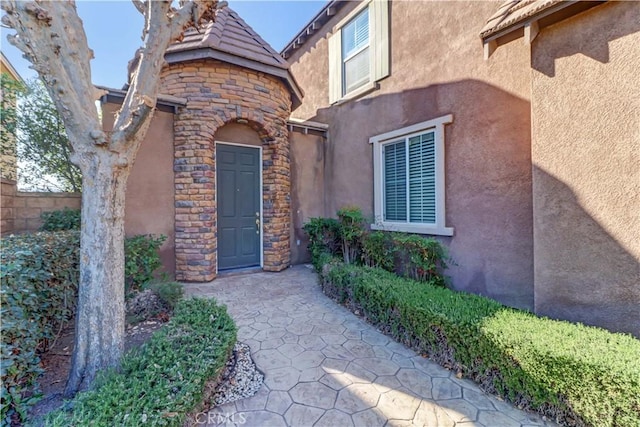 entrance to property featuring stone siding and stucco siding