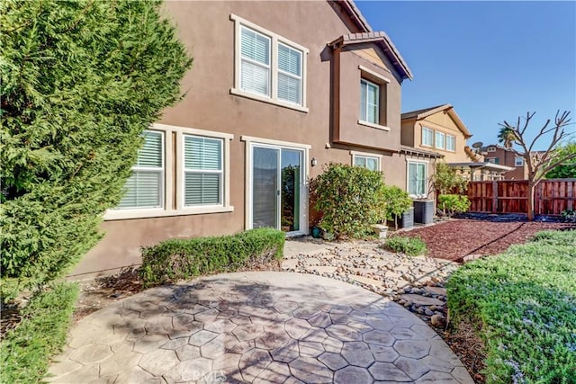 back of house with fence, a patio, and stucco siding