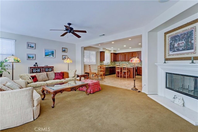 living room with visible vents, a ceiling fan, a glass covered fireplace, light colored carpet, and recessed lighting