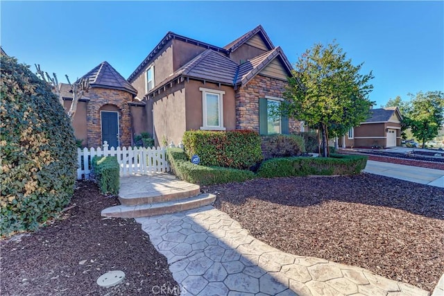 view of front of house with stone siding, fence, and stucco siding