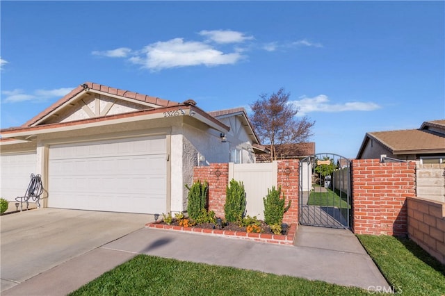 view of front of property with an attached garage, fence, driveway, a gate, and stucco siding