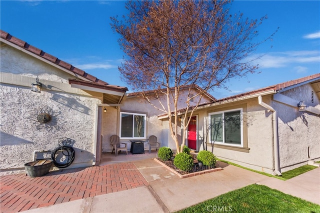 view of exterior entry with a patio area and stucco siding