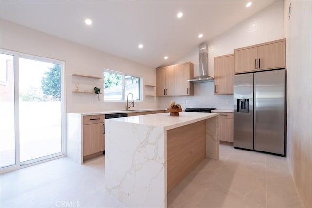 kitchen with a center island, open shelves, light brown cabinetry, wall chimney range hood, and stainless steel fridge