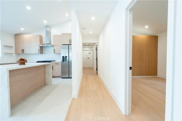 kitchen featuring open shelves, tasteful backsplash, modern cabinets, stainless steel fridge, and wall chimney exhaust hood