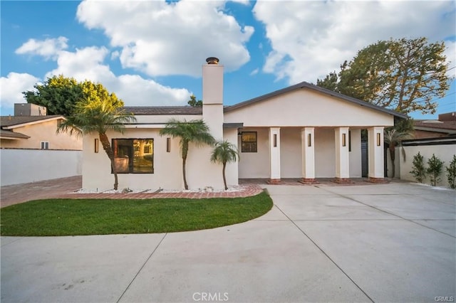 view of front of property featuring a front yard, a chimney, and stucco siding