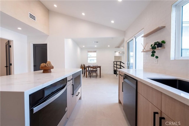 kitchen with light stone countertops, light brown cabinets, dishwasher, and modern cabinets