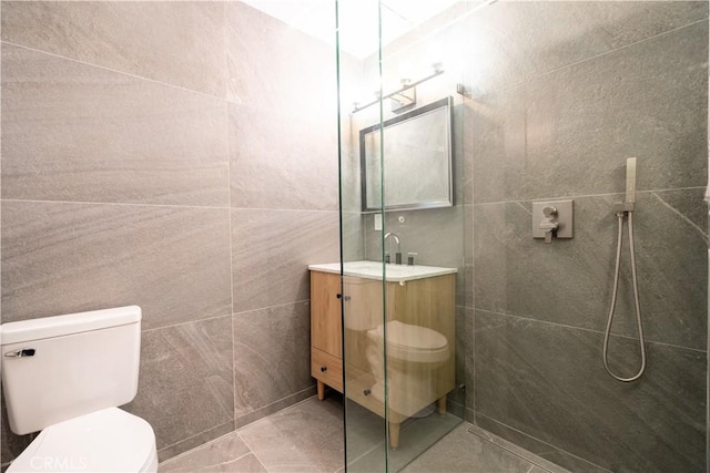 bathroom featuring toilet, walk in shower, tile walls, and vanity