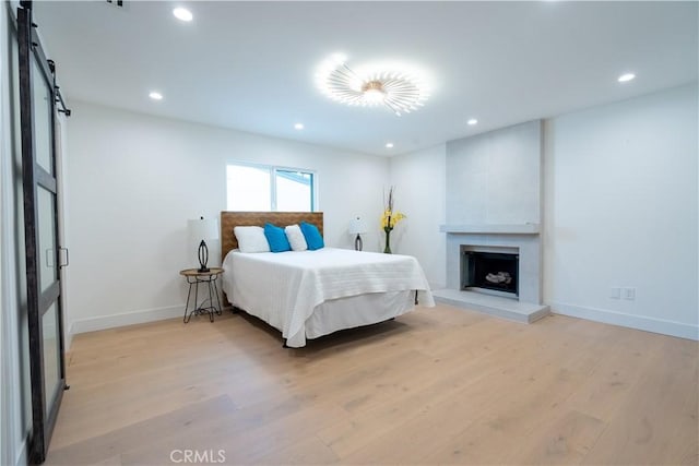 bedroom with recessed lighting, baseboards, a fireplace, and light wood finished floors