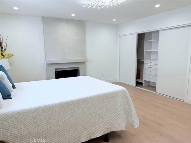 bedroom with recessed lighting, a closet, a fireplace, and light wood-style floors