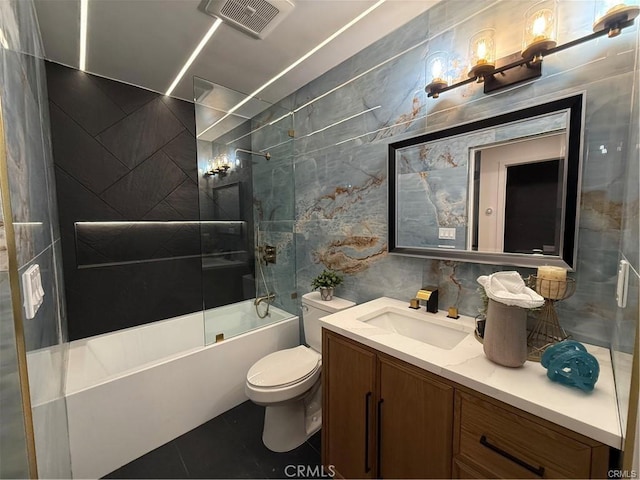 bathroom featuring toilet, vanity, visible vents, tile walls, and  shower combination