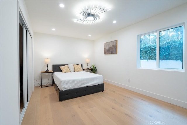 bedroom with light wood-style flooring, baseboards, a closet, and recessed lighting