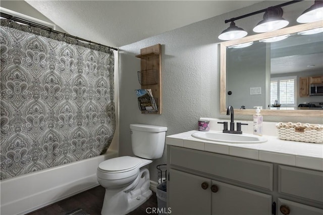 bathroom with toilet, shower / bath combo, vanity, and a textured wall