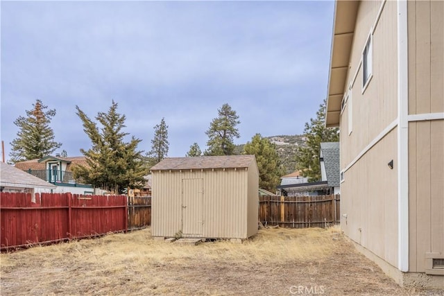 view of yard with a fenced backyard, a storage unit, and an outbuilding