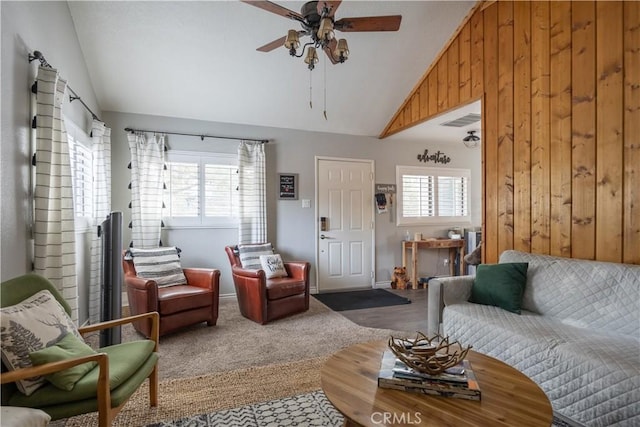 living area featuring visible vents, vaulted ceiling, wooden walls, and ceiling fan