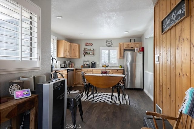 kitchen featuring dark wood-style flooring, stainless steel appliances, light countertops, light brown cabinetry, and a sink