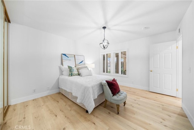 bedroom featuring baseboards, light wood-style flooring, and an inviting chandelier