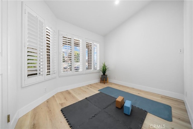 workout area featuring vaulted ceiling, baseboards, and wood finished floors