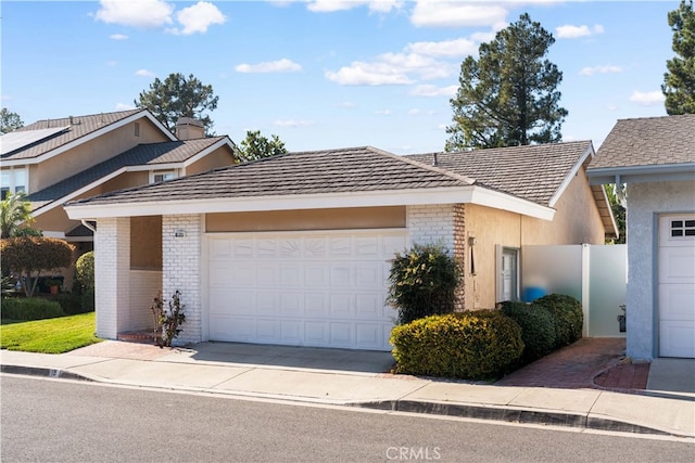 view of front of property with brick siding, driveway, an attached garage, and stucco siding