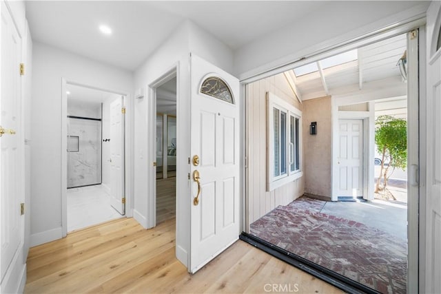 foyer entrance with lofted ceiling, light wood-style flooring, and baseboards