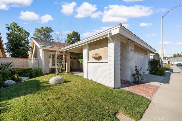 view of side of property featuring a garage, brick siding, fence, a yard, and driveway