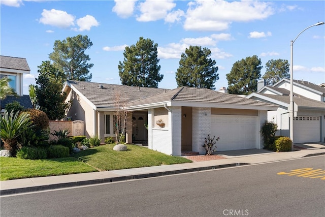 ranch-style home with an attached garage, a front lawn, concrete driveway, and brick siding