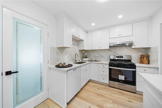 kitchen with gas stove, white cabinets, a sink, dishwasher, and under cabinet range hood