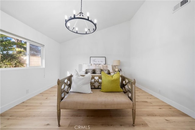 bedroom featuring baseboards, visible vents, wood finished floors, an inviting chandelier, and vaulted ceiling