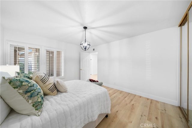 bedroom with light wood-style flooring, baseboards, and a chandelier