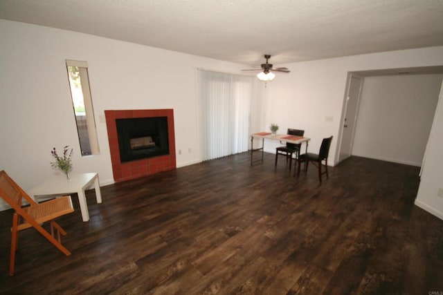 living room with a tile fireplace, ceiling fan, and wood finished floors