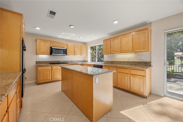 kitchen with light brown cabinetry, stainless steel microwave, gas cooktop, and visible vents